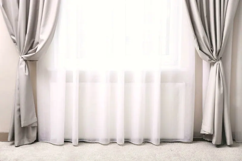 Floor-length drapery panels framing white sheers