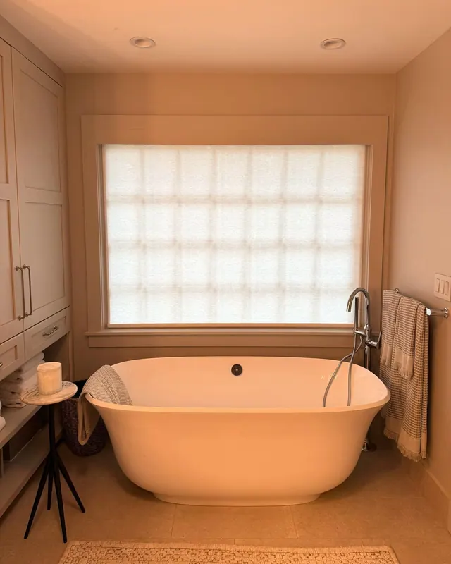 Light filtering shade glowing over a freestanding bathtub