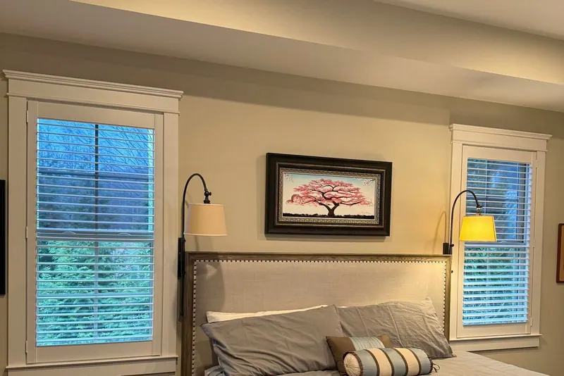 Plantation shutters on bedroom windows either side of the bed
