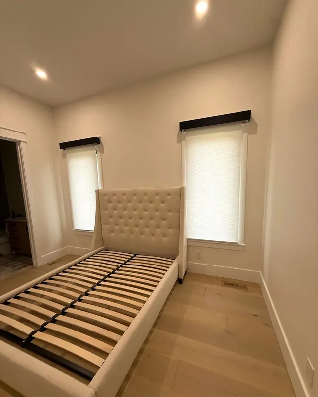 Two roller shades with dark valances in a guest bedroom